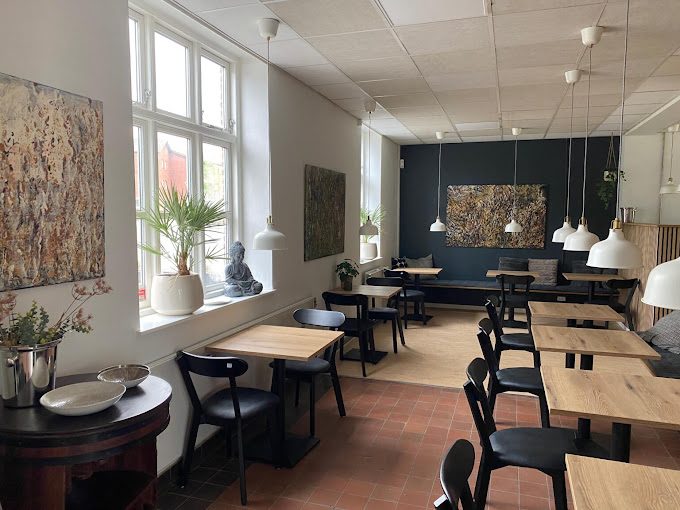 Caféens lokale med borde og kunst på væggene